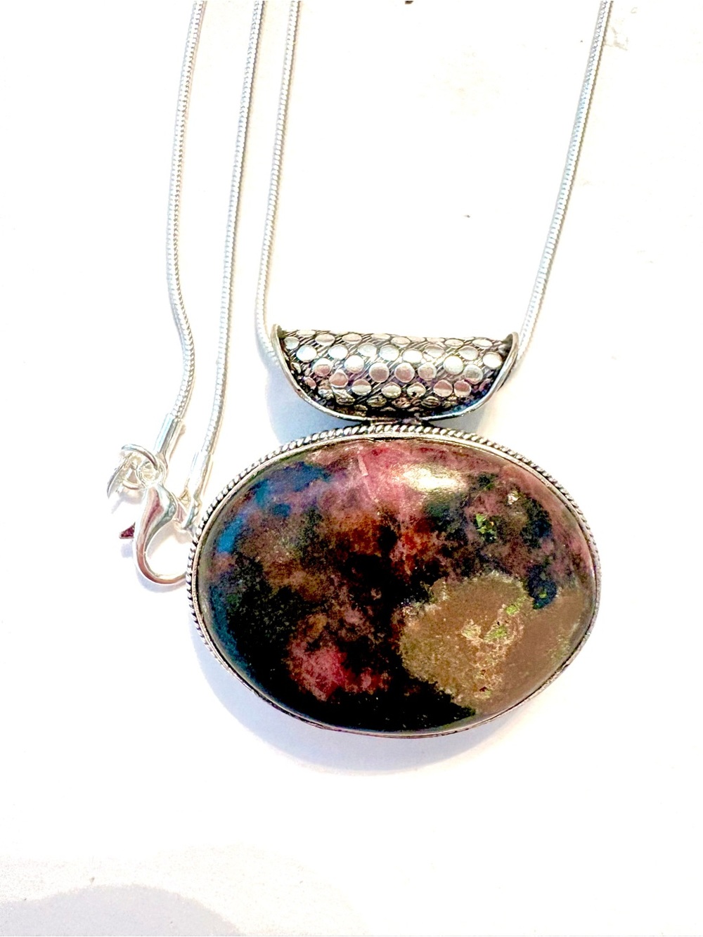 925 marked, Rhodonite pendant with a pretty design around, on a silver chain.